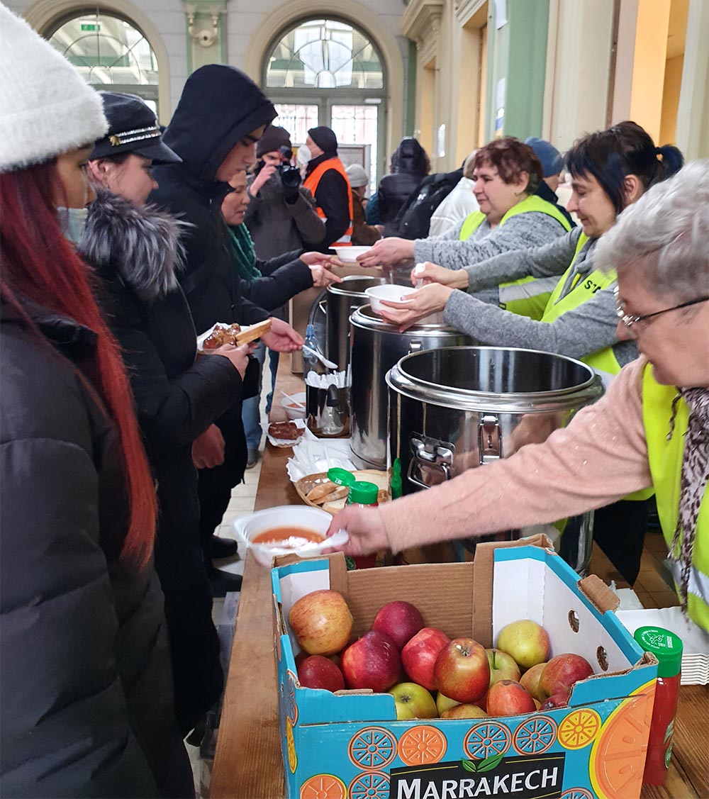 Volunteers give food to refugees arriving at train station